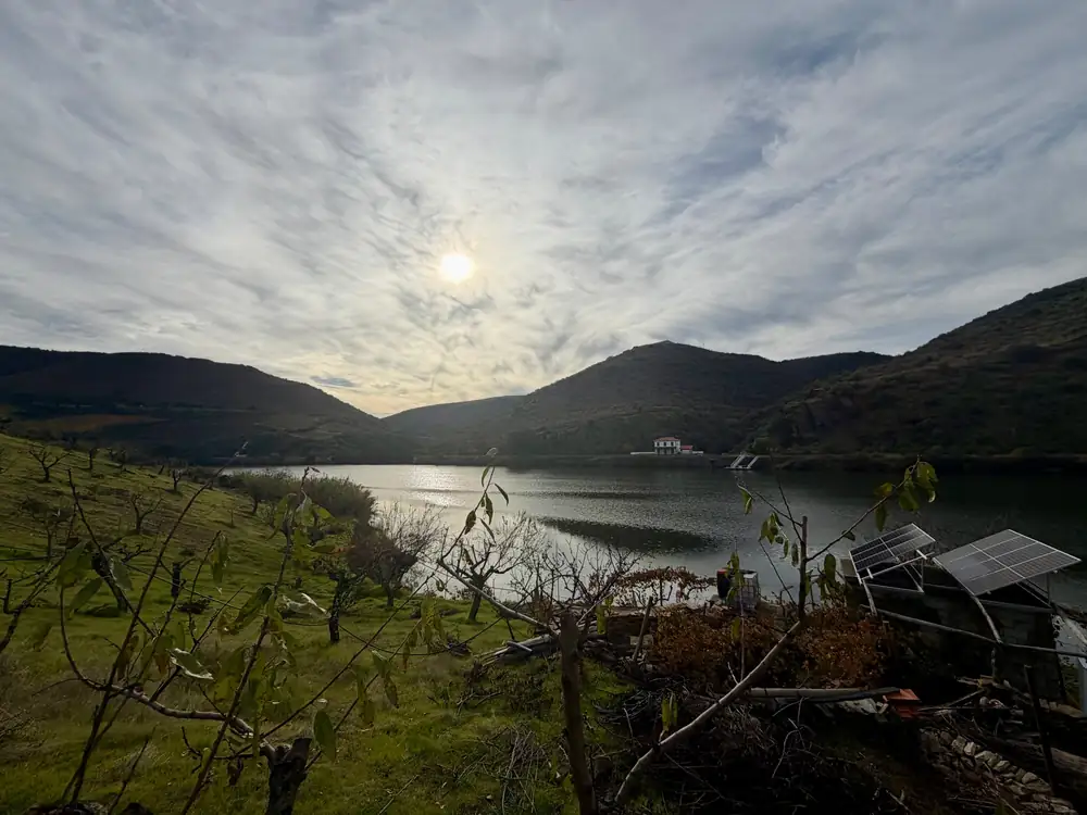 Sol de fim de tarde sobre o rio Douro, com amendoeiras na encosta e uma casa branca na margem oposta